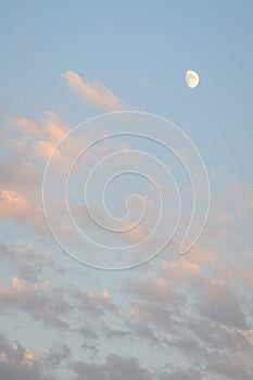Peaceful sky at dusk, light clouds and partial moon, as a nature background