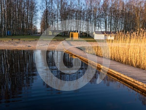 Peaceful spring landscape with a wooden footbridge in the lake, empty beach in the morning