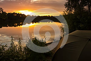 Peaceful Sunset carp fishing session. Golden sky and calm water