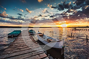 Peaceful sunset with dramatic sky and boats and a jetty