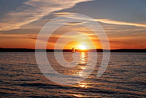 Peaceful sunset on sea. Sailing yacht on the background of the setting sun. Focus on the foreground