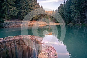 Peaceful sunset on a small lake in the middle of the woods. Trees reflection on the water surface. Autumn evening in the