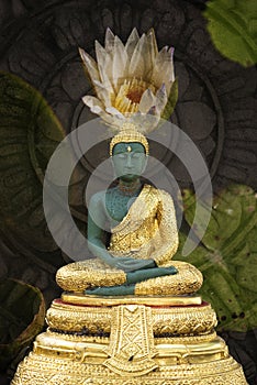 A peaceful superimposed and double exposure images of Green and Golden Buddha statue with a white lotus.