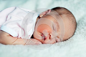 Peaceful sweet newborn infant baby lying on bed while sleeping in a bright room