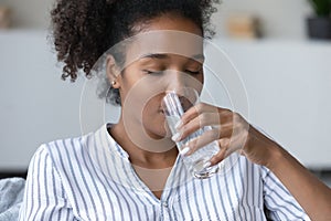 Peaceful teen millennial Black girl satisfying thirst, drinking water