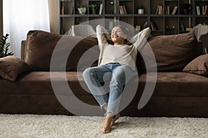 Peaceful teenage female recline on cozy sofa in modern flat