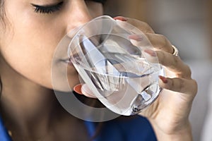 Peaceful thirsty young Indian woman drinking clear water