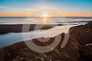 Peaceful view of sun rising over calm sea from rock pier in barcelona city at besos estuary photo