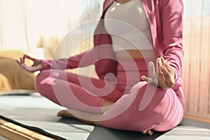 Peaceful woman having meditation session, sitting in lotus position. Yoga, meditation and healthy lifestyle concept
