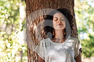 Peaceful woman leaning against a tree with her eyes closed photo