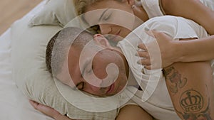 Peaceful woman lying in bed with husband and kissing him