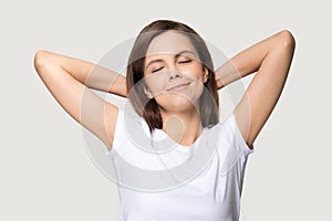 Peaceful woman putting hands behind head isolated on grey background