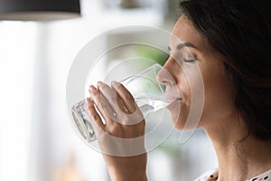 Peaceful woman satisfying thirst, drinking fresh pure clear cold water