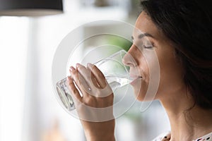 Peaceful woman satisfying thirst, drinking fresh pure clear cold water photo
