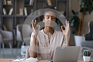 Peaceful young african ethnicity woman reducing stress at workplace.