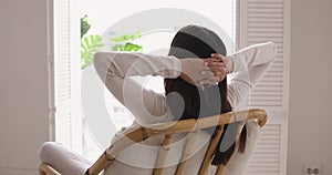 Peaceful young brunette woman resting in comfortable chair.