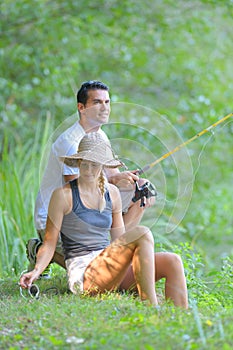 Peaceful young couple fishing by pond in autumn