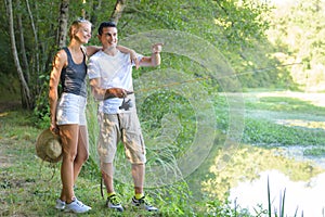 Peaceful young couple fishing by pond in autumn