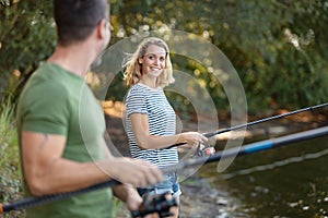 peaceful young couple fishing by pond in autumn