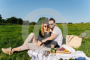 Peaceful young couple having a picnic on a spring grassfield in a countryside