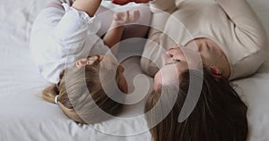 Peaceful young mother and toddler daughter kid relaxing on bed