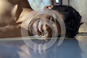 Peacefulness concept. Creative portrait of a young man lying on a reflective floor photo
