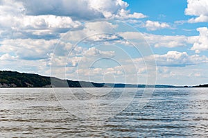 Peacful view of waterwith reflactions, hills with trees and blue sky with clouds