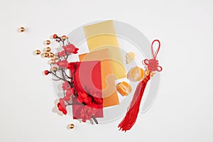 A peach blossom branch, red envelopes, tangerines and a decorative string stand out on a minimalist white background. Tet