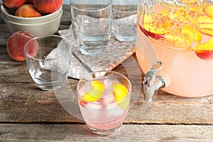 Peach cocktail in glass and jar with tap on tabl