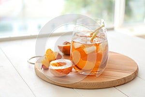 Peach cocktail in glass on wooden board