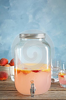 Peach cocktail in jar with tap on table
