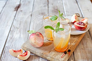 Peach cocktail with mint on white wooden background