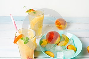 Peach cold orange refreshing juice cocktail in a glass with ice and pieces of fruit and mint in the summer. top view on a light