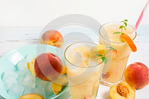 Peach cold orange refreshing juice cocktail in a glass with ice and pieces of fruit and mint in the summer. top view on a light