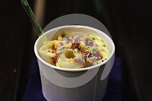 Peach fried ice cream with dragee in a paper cup with plastic spoons