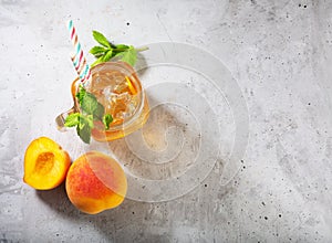 Peach ice tea on concrete gray background with mint and ice