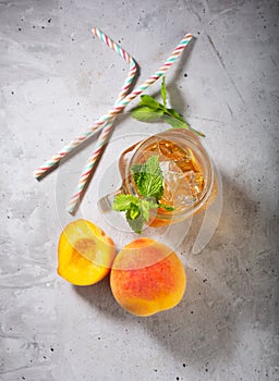 Peach ice tea on concrete gray background with mint and ice