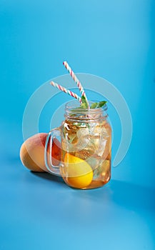 Peach ice tea drink on blue background with mint and ice