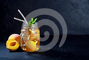 Peach ice tea drink on dark background with mint and ice