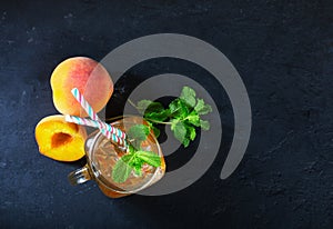 Peach ice tea drink on dark background with mint and ice