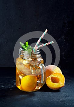 Peach ice tea drink on dark background with mint and ice