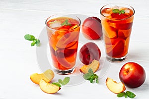 Peach ice tea in a glass with mint on a white wooden table(selective focus