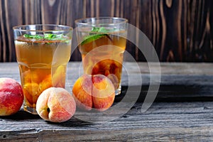 Peach ice tea in a glass with mint on wooden table