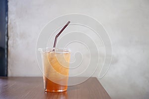 Peach ice tea in plastic cup on wooden table