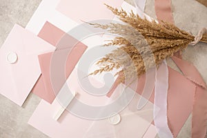 Peach mock up composition of weeding invitation paper envelopes, seal wax, ribbon. Handcraft holiday, event. Top view.