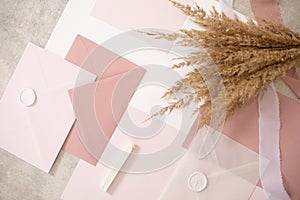 Peach mock up composition of weeding invitation paper envelopes, seal wax, ribbon. Handcraft holiday-event. Top view.