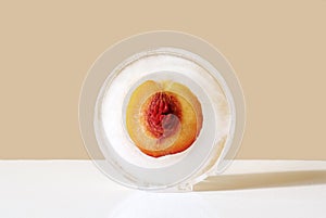 Peach with seed in round ice. Concept of shock freezing of fruits and frozen food. Preservation of summer vitamins. Juicy