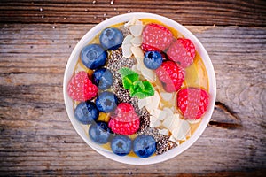 Peach smoothie bowl with raspberries, blueberries, chia seeds and almonds