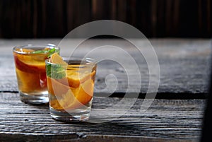 Peach Tea with pieces of fruit and mint on a wooden background,