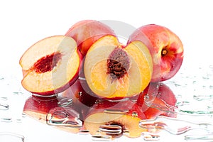 Peach whole and cutted into two halves in water drops on white background isolated close up